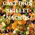 A close of photo of nachos with jalapenos, black olives, cheese, onions, tomatoes, and chips.