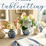 Blue and white table setting with chinoiserie style plates and vases and an embroidered dinner napkin on top of the plate embroidered with a blue hydrangea in the corner.