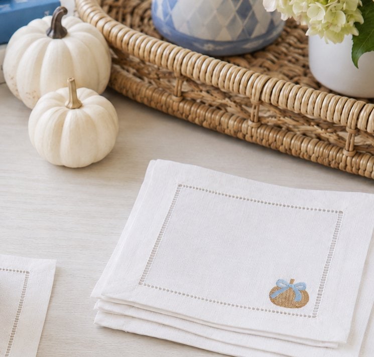 Linen napkin embroidered with woven pumpkin on fall-themed table.