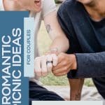 Two men who got engaged on a picnic date. They are sitting next to each other, and showing the ring to friends with smiles on their faces.