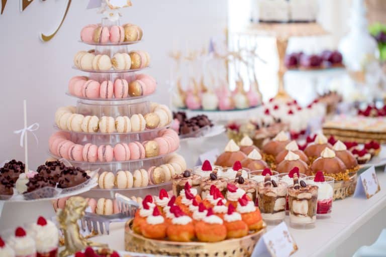 Beautiful table set with many different kinds of pink, red, and white finger food desserts for a bridal brunch