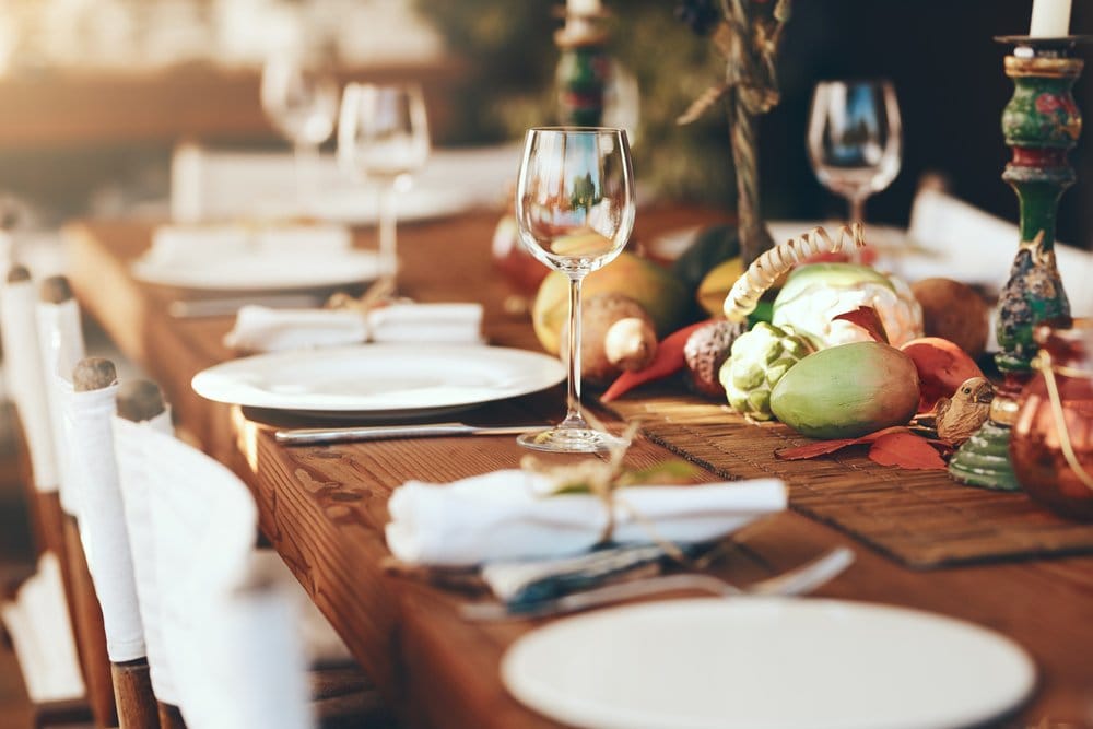 Table set for dinner with glasses, plates, and decor at home. White dishes, fall scene.